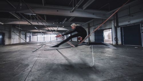 Digital composite image of woman jumping over rope in warehouse