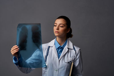 Doctor holding medical x-ray against gray background