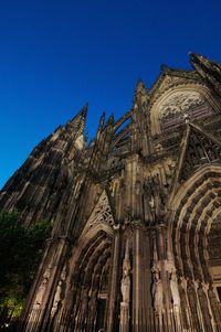 Low angle view of cologne cathedral against clear blue sky at dusk