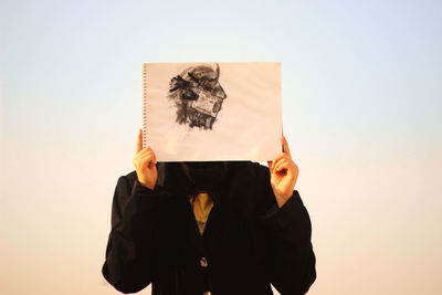 Man holding drawing against clear sky