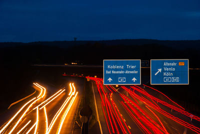 Light trails on road against sky at night