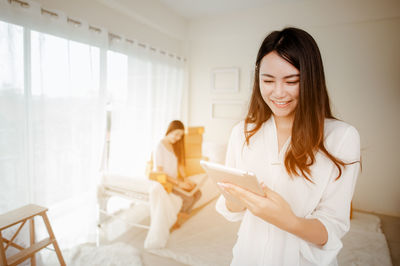 Young woman using phone while standing at home