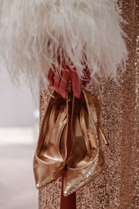 Fashion model dressed in a golden haute couture boudoir dress and holding high heels shoes