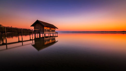 House by sea against sky during sunset