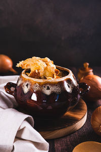 French onion soup with melted cheese and croutons in a pot on the table vertical view