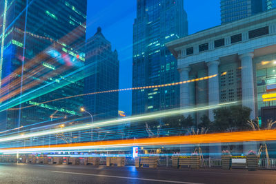 Light trails on street amidst buildings in city at night