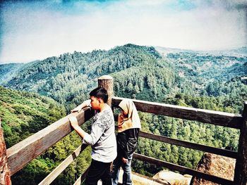 Full length rear view of woman on railing against mountain