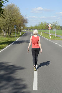 Rear view of woman walking on road against sky