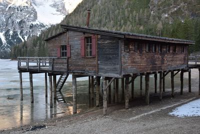 Built structure by lake against trees during winter