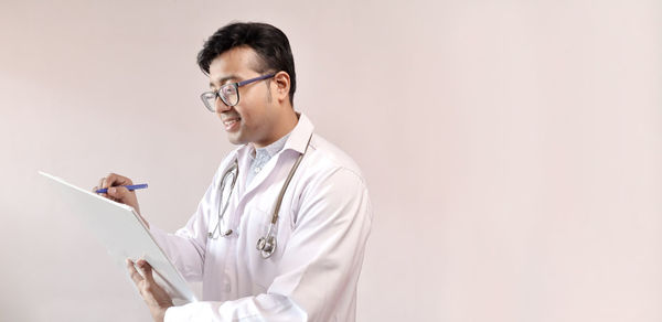 Side view of young man standing against white background