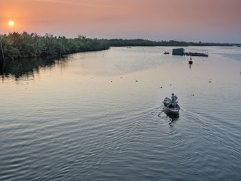 Man in sea against sky during sunset