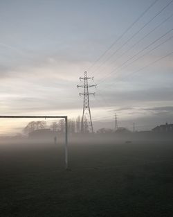 Electricity pylon on field against sky