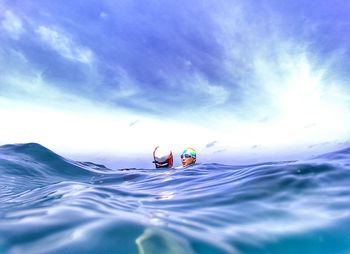 Water surface level of people swimming in sea against sky