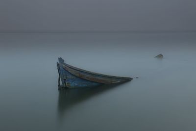 Boat sinking in sea against sky