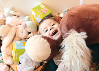 Cute young boy playing among a mountain of soft plush toys
