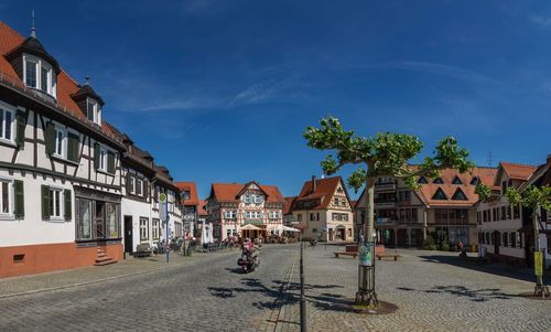 Buildings by street in city against sky