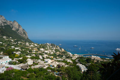 High angle view of sea and mountains against clear blue sky