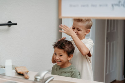 Two boys are getting ready in a bathroom,