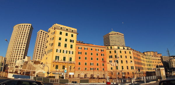 Buildings in city against clear blue sky