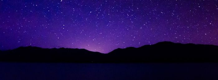 Scenic view of silhouette mountains against sky at night