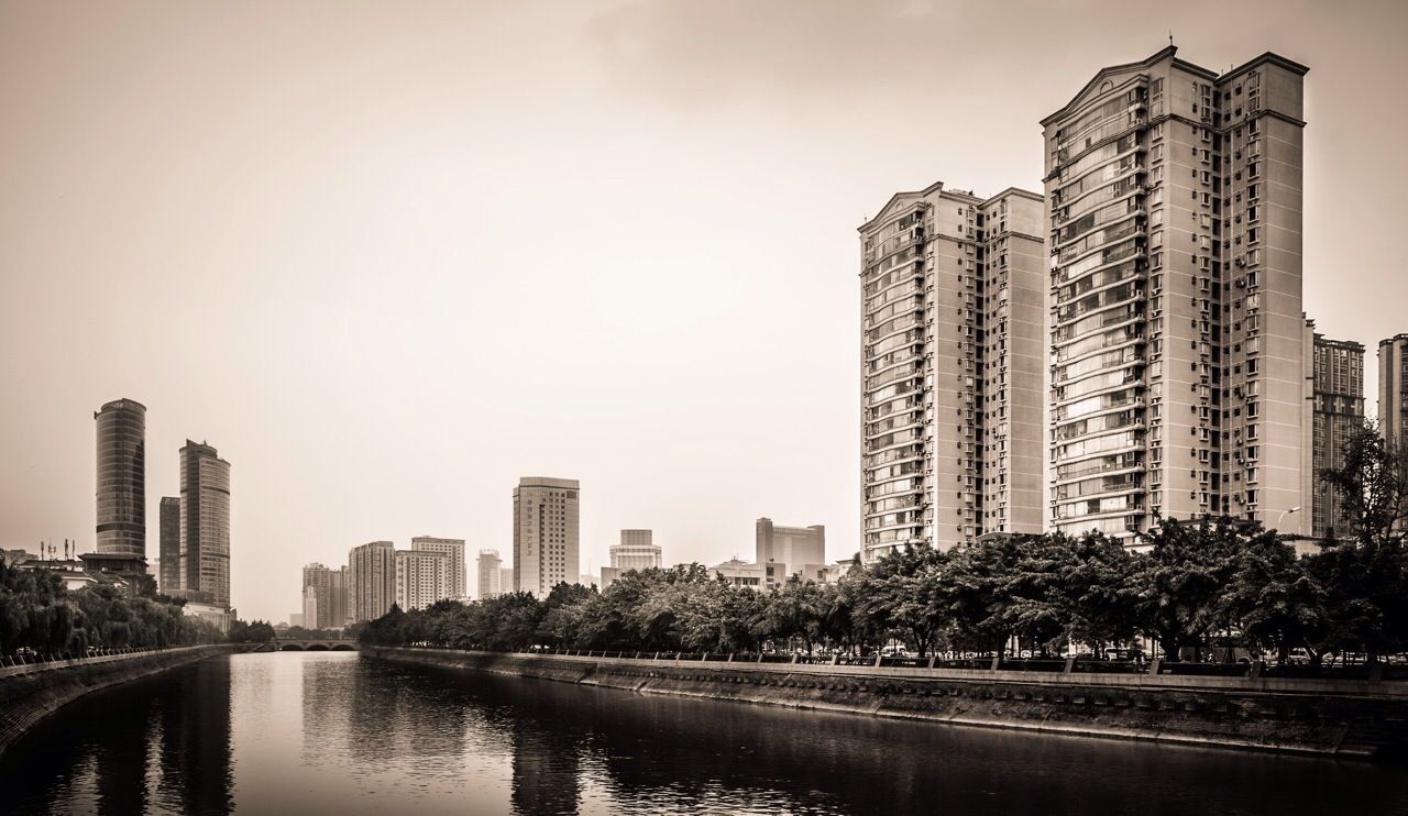 architecture, building exterior, city, built structure, skyscraper, water, river, waterfront, cityscape, tall - high, office building, urban skyline, modern, reflection, sky, tower, clear sky, tree, financial district, skyline