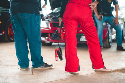 Low section of people standing against car at garage