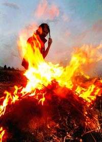 Young woman with bonfire against sky at night