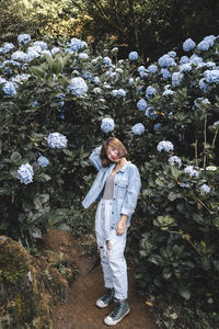 Full length portrait of woman standing on flowering plants