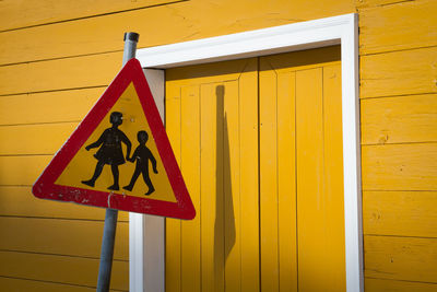 Close-up of warning sign on yellow wall