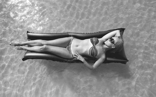 Directly above shot of woman relaxing on inflatable raft over swimming pool