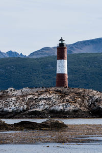 Lighthouse by sea against sky