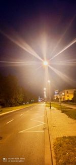 Illuminated city street against sky