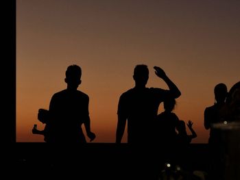 Silhouette people against orange sky