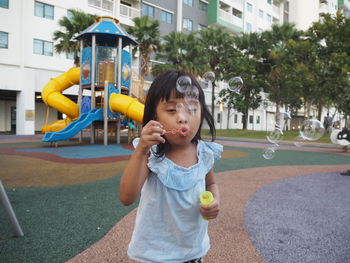 Cute girl blowing bubbles in playground