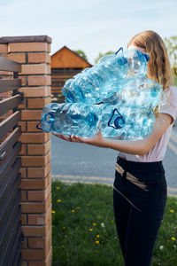 Woman holding blue umbrella standing against built structure