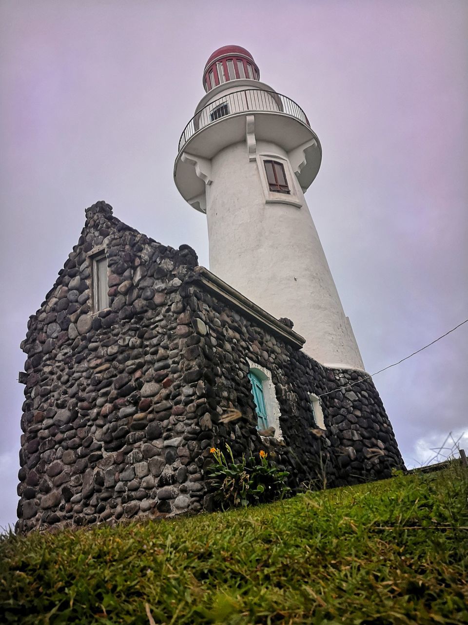 architecture, lighthouse, built structure, building exterior, tower, sky, building, low angle view, guidance, history, nature, the past, no people, travel destinations, security, protection, plant, cloud, outdoors, house, landmark, day, travel, grass