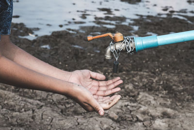 Close-up of person collecting water from locked faucet