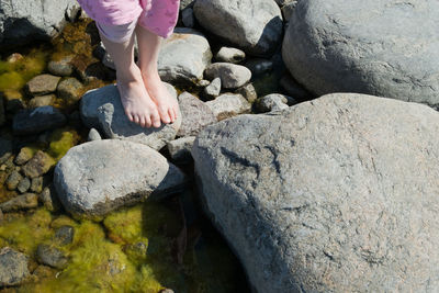 Low section of person on rocks at shore