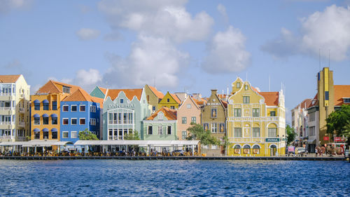 Buildings by river against sky