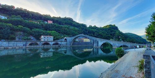 Arch bridge over river against sky