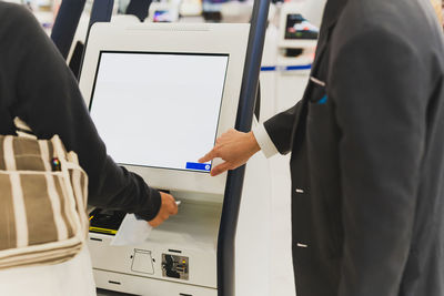 Airport staff helping woman passenger doing self check in scanning boarding pass at airport
