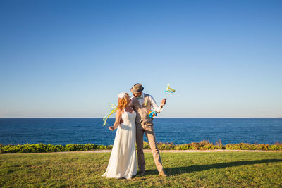 Happy couple standing against sea and sky