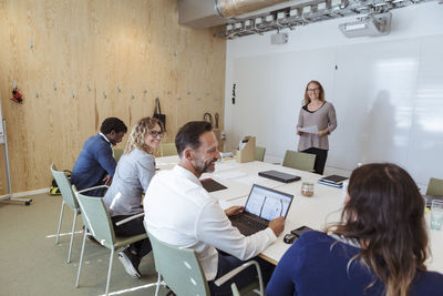 Smiling male and female business colleagues sharing ideas in office meeting