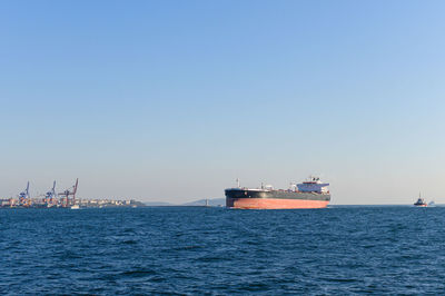 Ship sailing on sea against clear blue sky