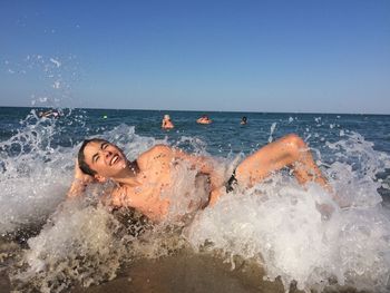 Man splashing water in sea against clear sky