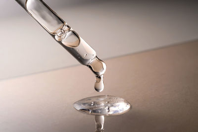 Pipette with serum, gel, oil or other cosmetic product on a beige background.