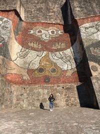 Full length of woman standing against wall