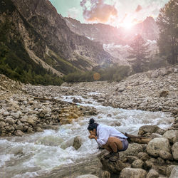 Side view of woman drinking water at riverbank