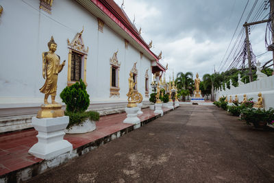 Statues and temple building against cloudy sky