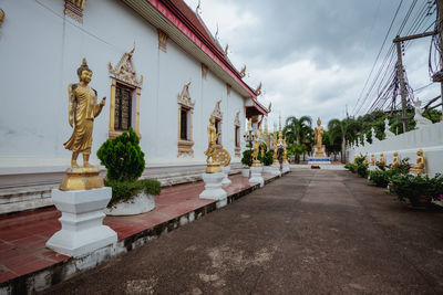 Statue of statues by building against sky